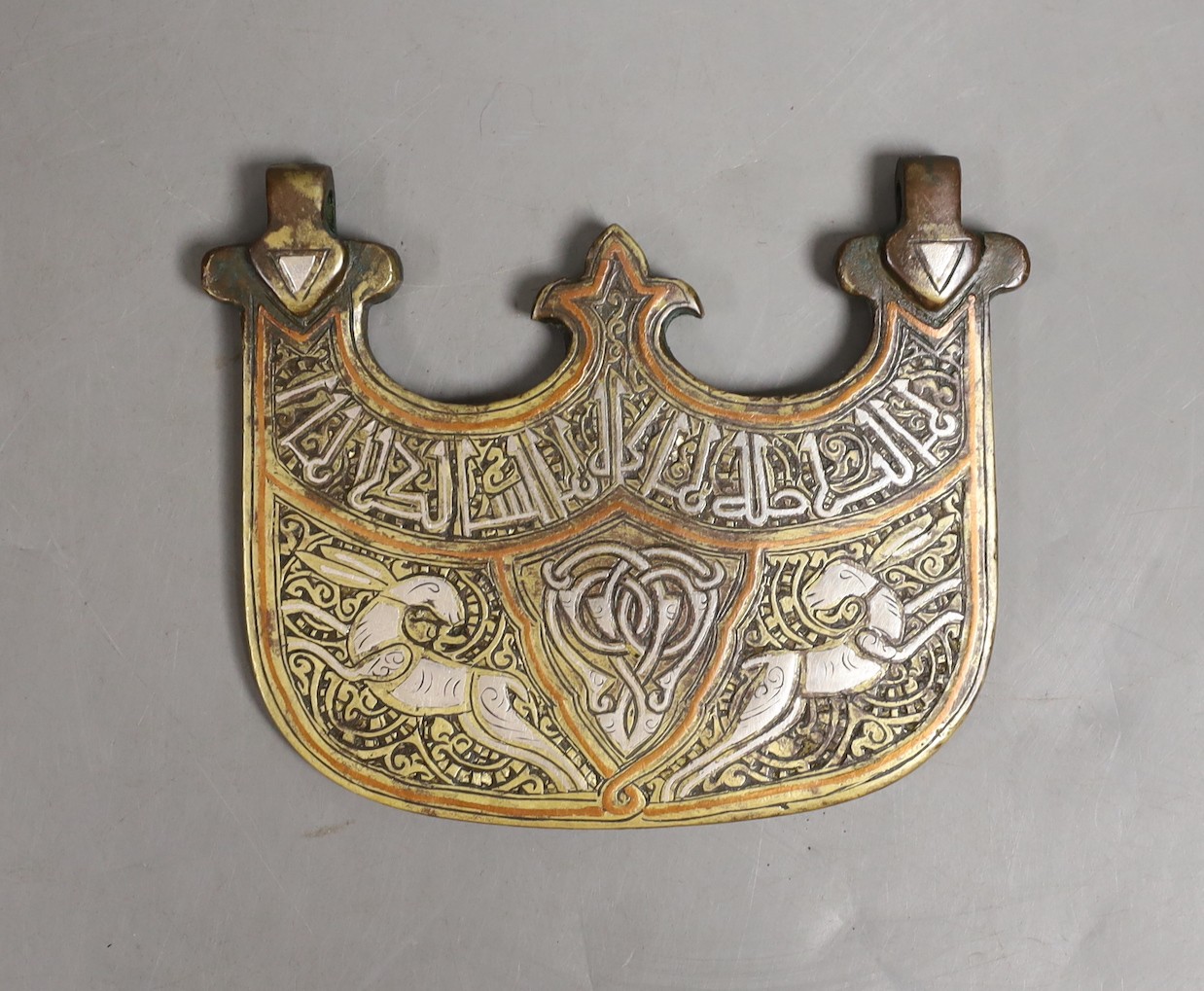 An Islamic bronze and mixed metal pendant, 10 cms wide
